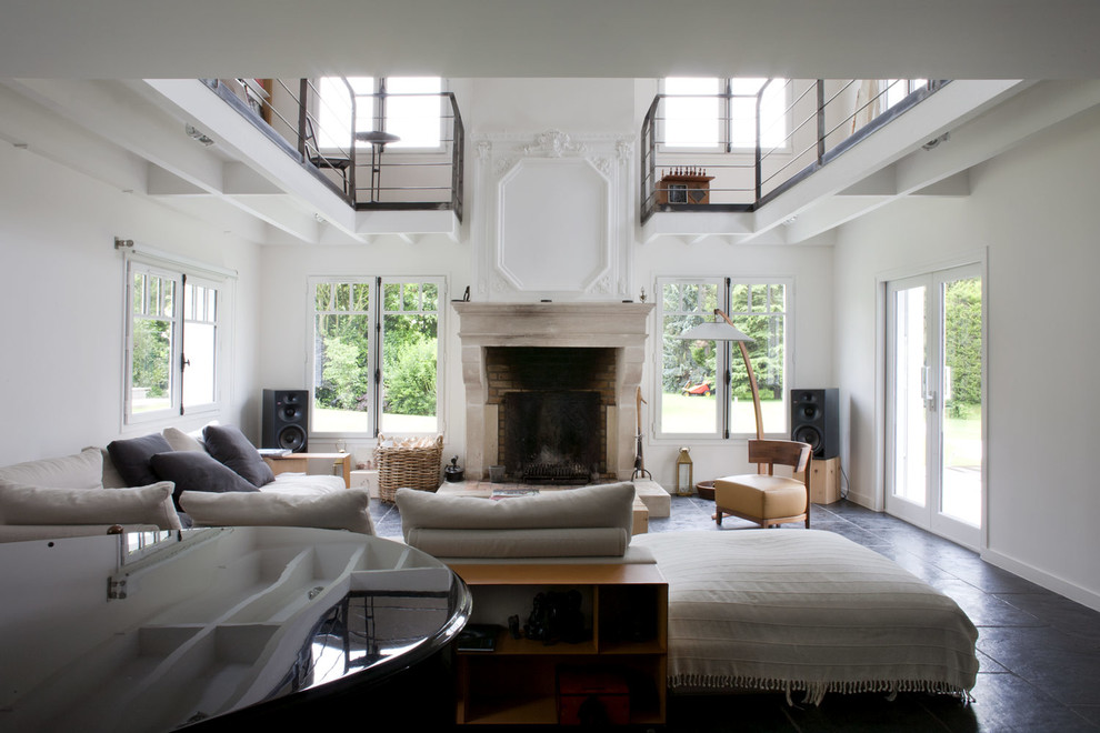 Offenes Eklektisches Wohnzimmer mit weißer Wandfarbe, Kamin, Kaminumrandung aus Stein und schwarzem Boden in Paris