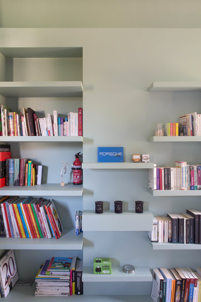 Cette image montre un salon minimaliste avec une bibliothèque ou un coin lecture et un mur blanc.