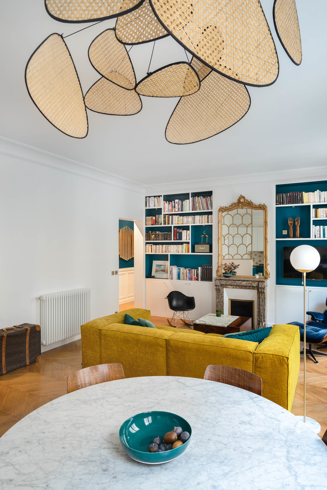 This is an example of a medium sized scandi open plan living room in Paris with a reading nook, white walls, light hardwood flooring, a standard fireplace, a stone fireplace surround, a wall mounted tv, brown floors and feature lighting.