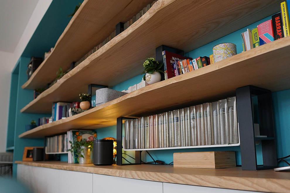 Inredning av ett minimalistiskt mellanstort separat vardagsrum, med ett bibliotek, blå väggar, mörkt trägolv och en fristående TV