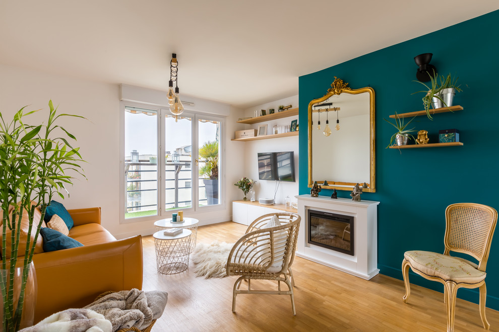 Offenes, Großes Modernes Wohnzimmer mit blauer Wandfarbe, Kamin, hellem Holzboden, TV-Wand und beigem Boden in Paris