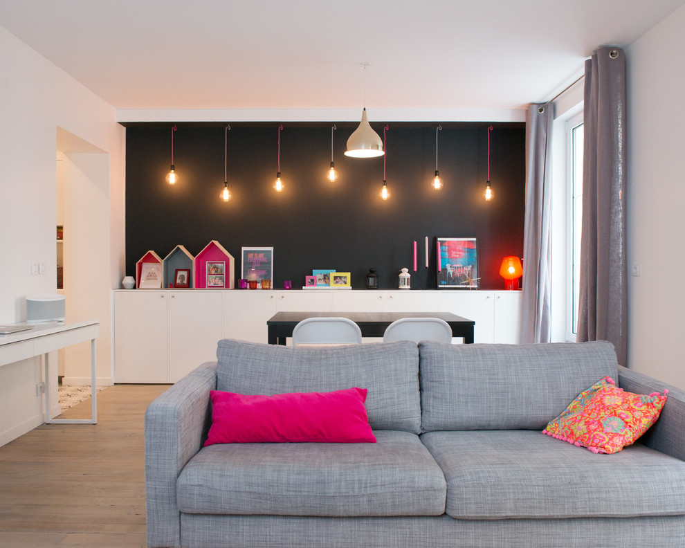 Immagine di un soggiorno scandinavo di medie dimensioni e aperto con pareti nere, parquet chiaro e nessun camino