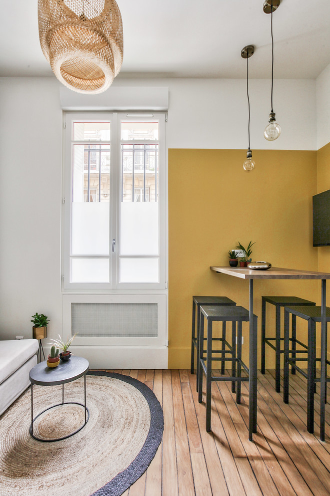 Стильный дизайн: открытая гостиная комната среднего размера в стиле лофт с желтыми стенами, паркетным полом среднего тона, коричневым полом и телевизором на стене без камина - последний тренд