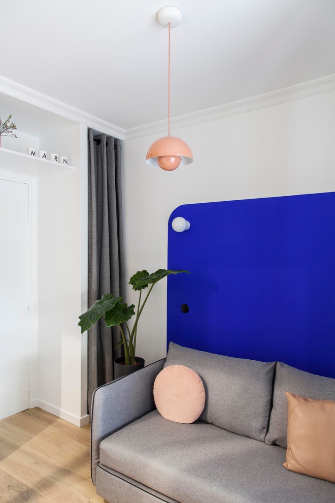 Diseño de salón abierto moderno pequeño con paredes azules, suelo de madera clara y suelo beige
