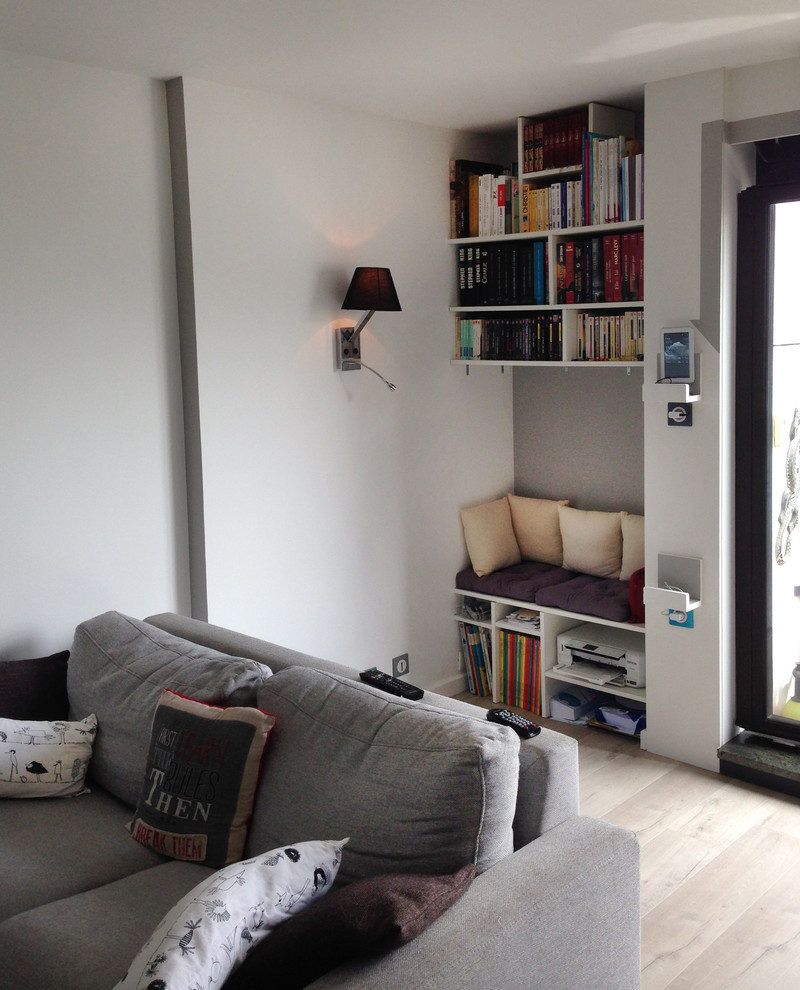 Immagine di un piccolo soggiorno minimal aperto con libreria, parquet chiaro, nessun camino e pareti grigie