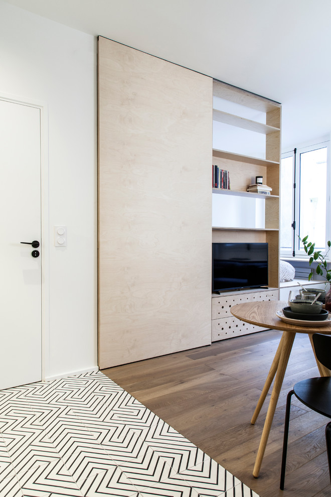 Идея дизайна: открытая гостиная комната среднего размера в скандинавском стиле с с книжными шкафами и полками, белыми стенами, паркетным полом среднего тона, мультимедийным центром, коричневым полом и деревянными стенами без камина