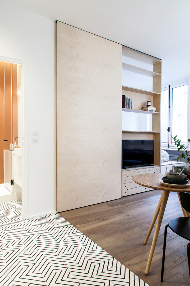 Идея дизайна: открытая гостиная комната среднего размера в скандинавском стиле с с книжными шкафами и полками, белыми стенами, паркетным полом среднего тона, мультимедийным центром, коричневым полом и деревянными стенами без камина