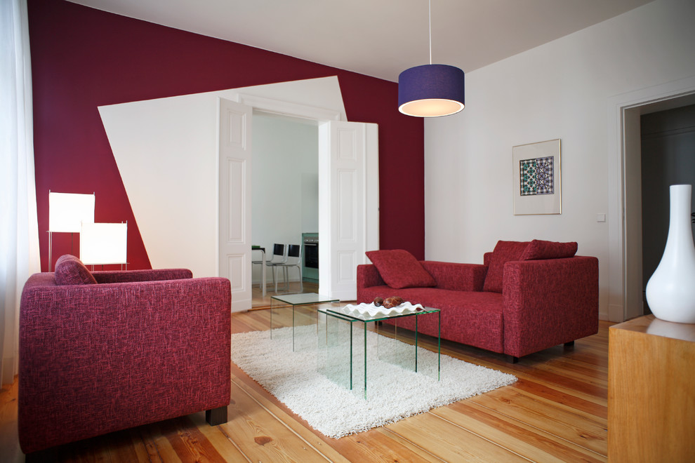 Modern inredning av ett mellanstort separat vardagsrum, med ett finrum, röda väggar och mellanmörkt trägolv