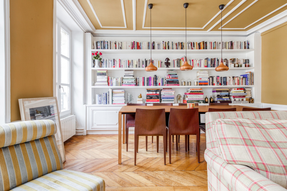 Foto de biblioteca en casa abierta tradicional renovada de tamaño medio con paredes amarillas, suelo de madera clara, todas las chimeneas, televisor independiente, suelo marrón y machihembrado
