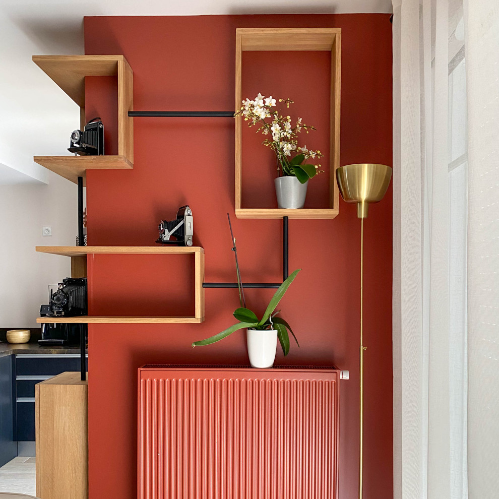 На фото: открытая гостиная комната среднего размера в современном стиле с с книжными шкафами и полками, полом из керамической плитки, бежевым полом и оранжевыми стенами без камина