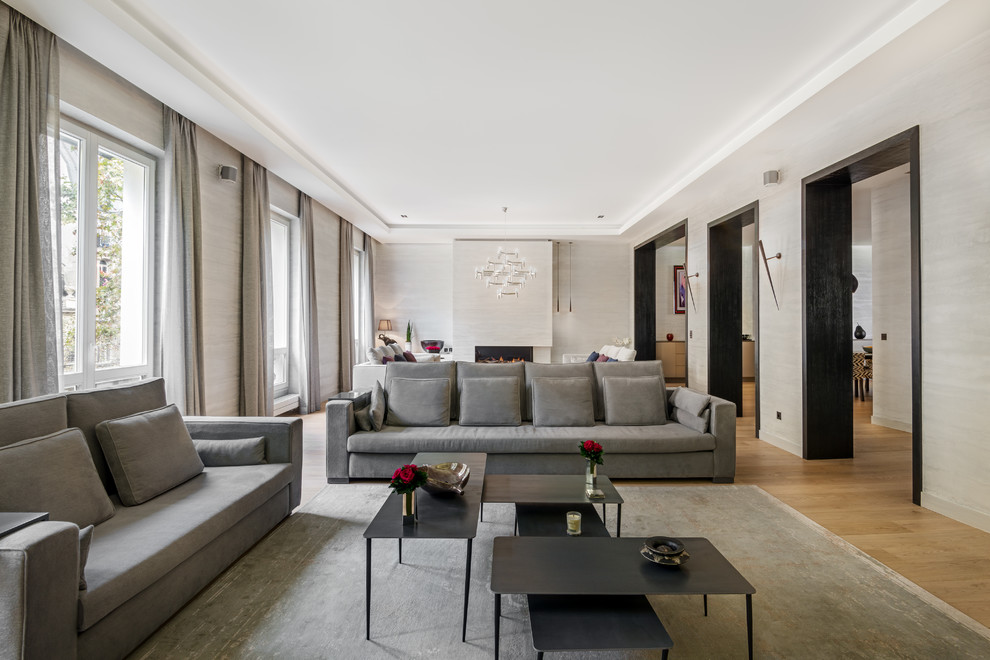 Стильный дизайн: большая гостиная комната в современном стиле с бежевыми стенами, светлым паркетным полом и подвесным камином - последний тренд