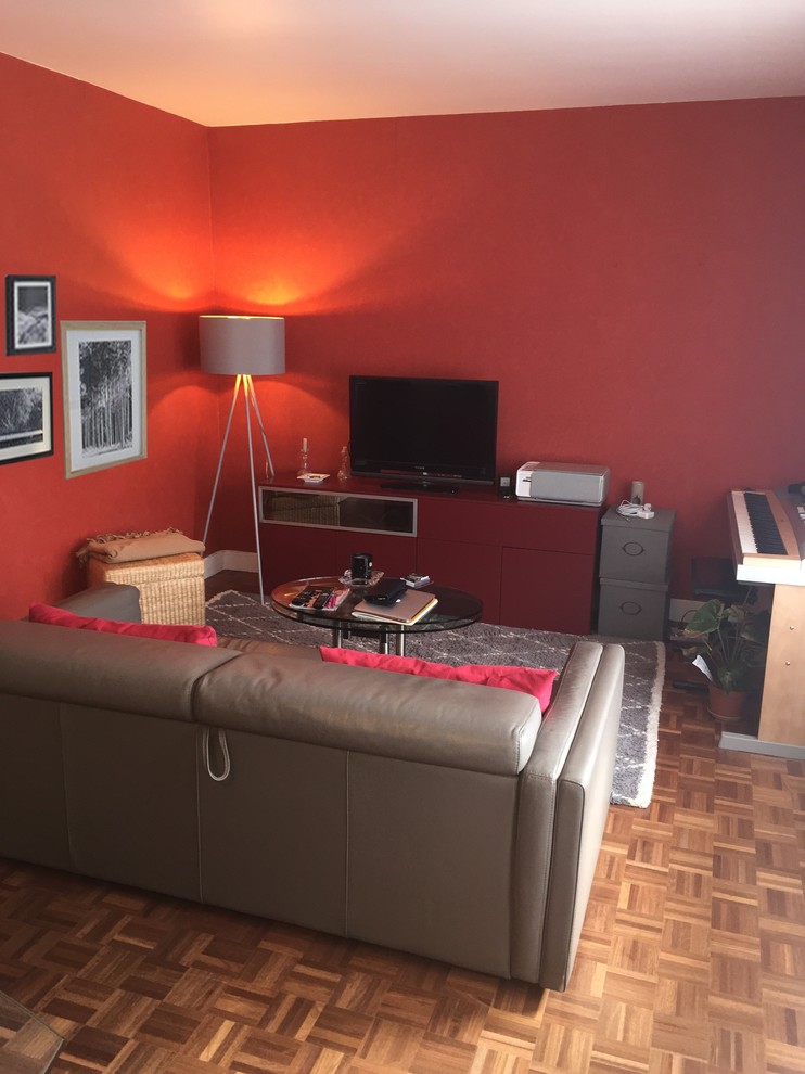 Modelo de salón cerrado tradicional de tamaño medio sin chimenea con paredes rojas, suelo de madera en tonos medios y televisor independiente