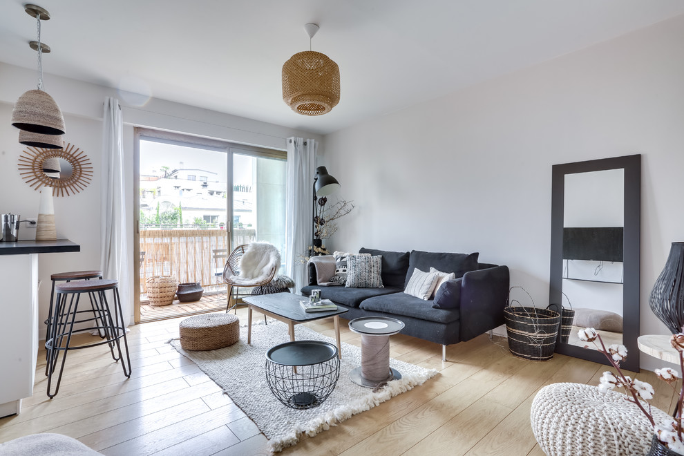 Offenes Nordisches Wohnzimmer ohne Kamin mit weißer Wandfarbe und hellem Holzboden in Paris