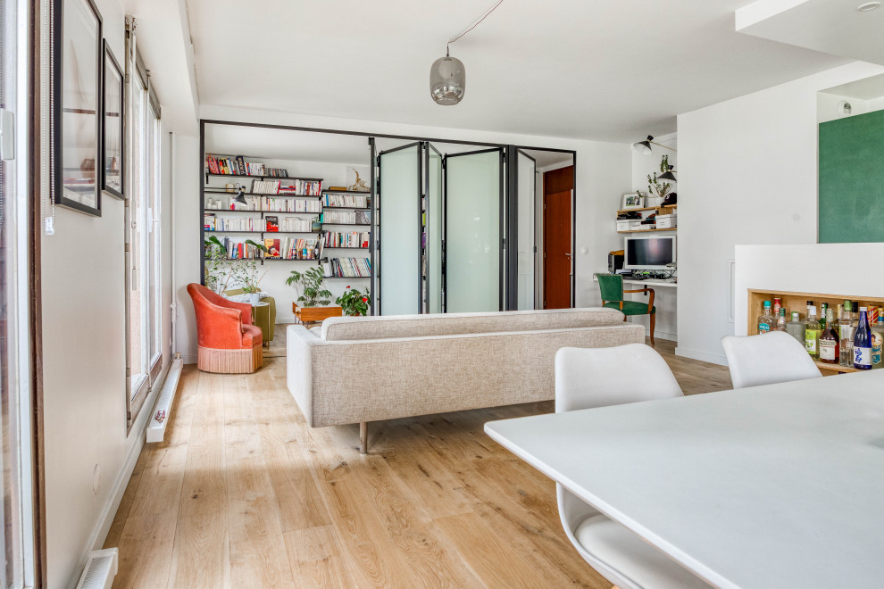Inspiration för ett stort funkis vardagsrum, med ett bibliotek, vita väggar och ljust trägolv
