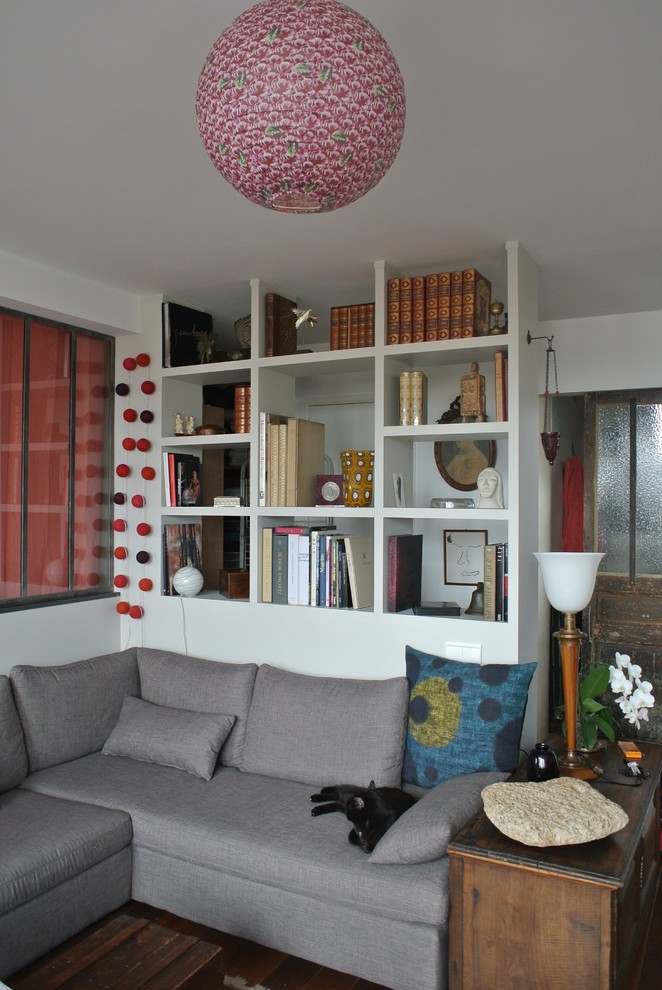 Идея дизайна: открытая гостиная комната среднего размера в стиле фьюжн с с книжными шкафами и полками, серыми стенами, паркетным полом среднего тона, угловым камином, фасадом камина из бетона и коричневым полом без телевизора
