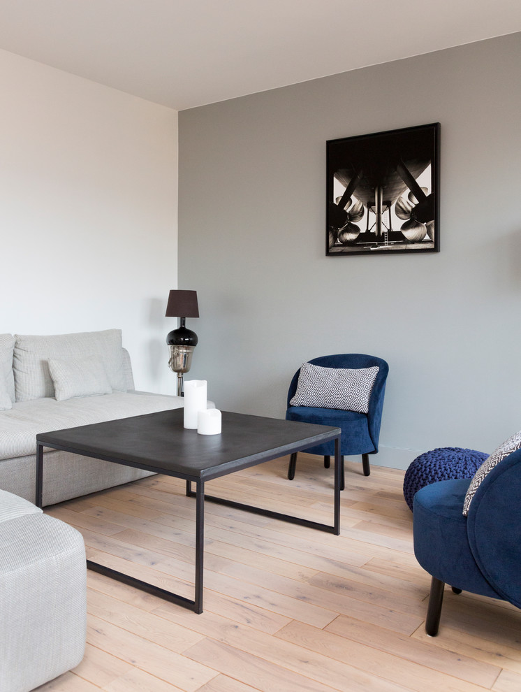Cette image montre un salon design de taille moyenne et ouvert avec un mur gris, parquet clair, aucune cheminée, un téléviseur indépendant et un sol beige.