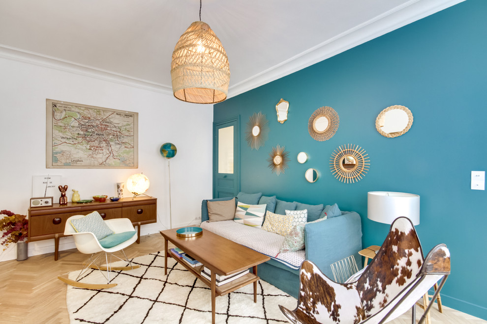 Стильный дизайн: гостиная комната в стиле фьюжн с синими стенами, светлым паркетным полом, бежевым полом и синим диваном - последний тренд