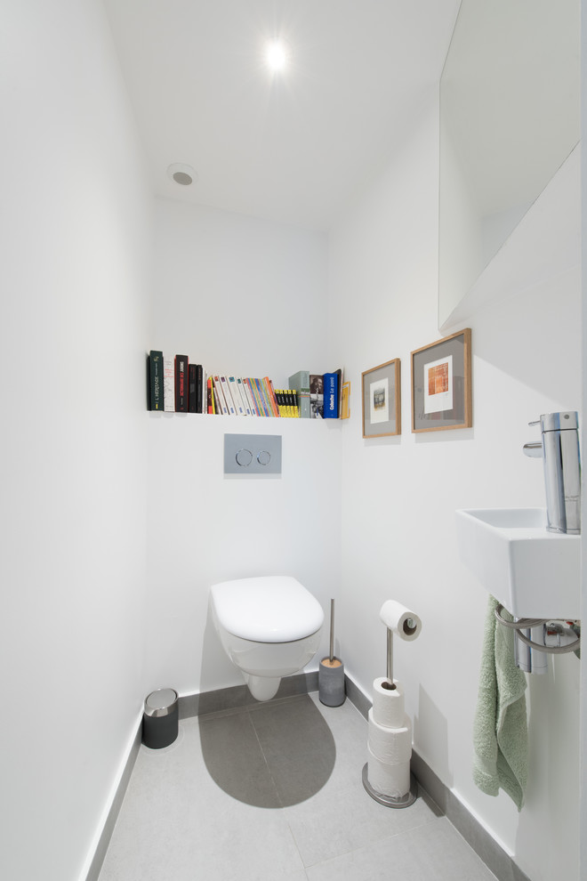 Aménagement d'un WC suspendu contemporain avec un mur blanc, un lavabo suspendu et un sol gris.