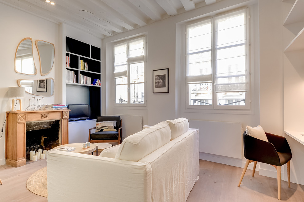 Идея дизайна: открытая гостиная комната среднего размера в скандинавском стиле с с книжными шкафами и полками, белыми стенами, темным паркетным полом, стандартным камином, фасадом камина из дерева, отдельно стоящим телевизором и коричневым полом