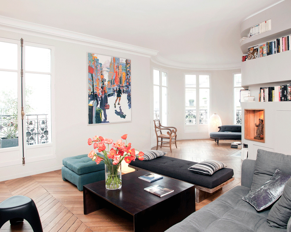 This is an example of a large contemporary open plan living room in Paris with a reading nook, white walls, medium hardwood flooring, no fireplace and no tv.