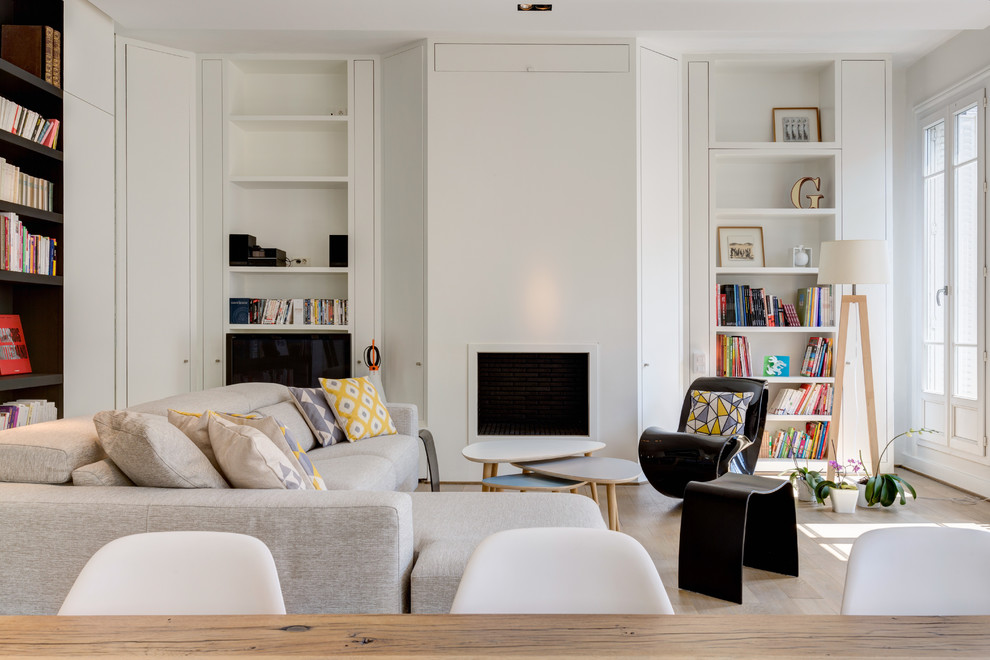 Idée de décoration pour un grand salon nordique ouvert avec une bibliothèque ou un coin lecture, un mur blanc, parquet clair, aucune cheminée, un téléviseur indépendant et un sol beige.