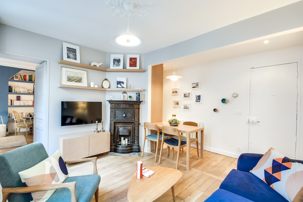 Mittelgroßes, Offenes Skandinavisches Wohnzimmer mit grauer Wandfarbe, hellem Holzboden, Kamin, Kaminumrandung aus Metall und TV-Wand in Paris