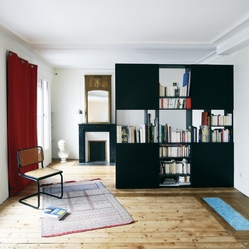 Esempio di un piccolo soggiorno bohémian aperto con libreria, pareti bianche, parquet chiaro, camino classico, cornice del camino in pietra e nessuna TV