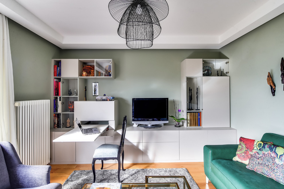 Modelo de salón abierto clásico renovado de tamaño medio sin chimenea con paredes verdes, suelo de madera clara y televisor independiente