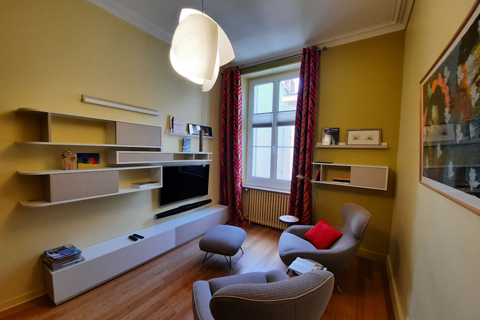 Inspiration pour un salon design fermé avec un mur jaune, un sol en bois brun et un téléviseur fixé au mur.