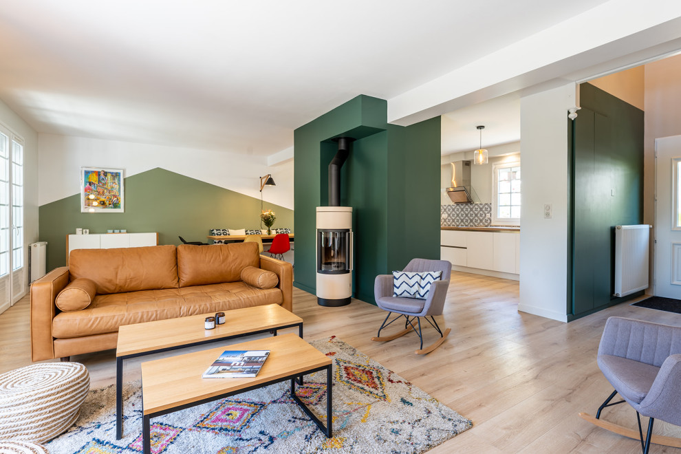 Ejemplo de salón abierto nórdico grande con paredes verdes, suelo de madera clara, estufa de leña y pared multimedia