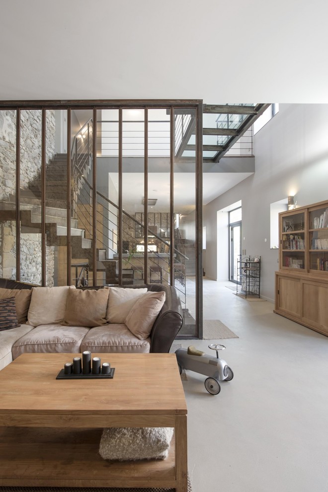 Стильный дизайн: открытая гостиная комната в стиле лофт с белыми стенами и бетонным полом - последний тренд