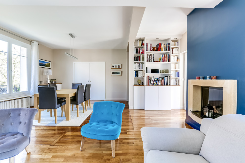 Exemple d'un salon tendance avec parquet clair, une cheminée standard, un manteau de cheminée en plâtre et un mur bleu.
