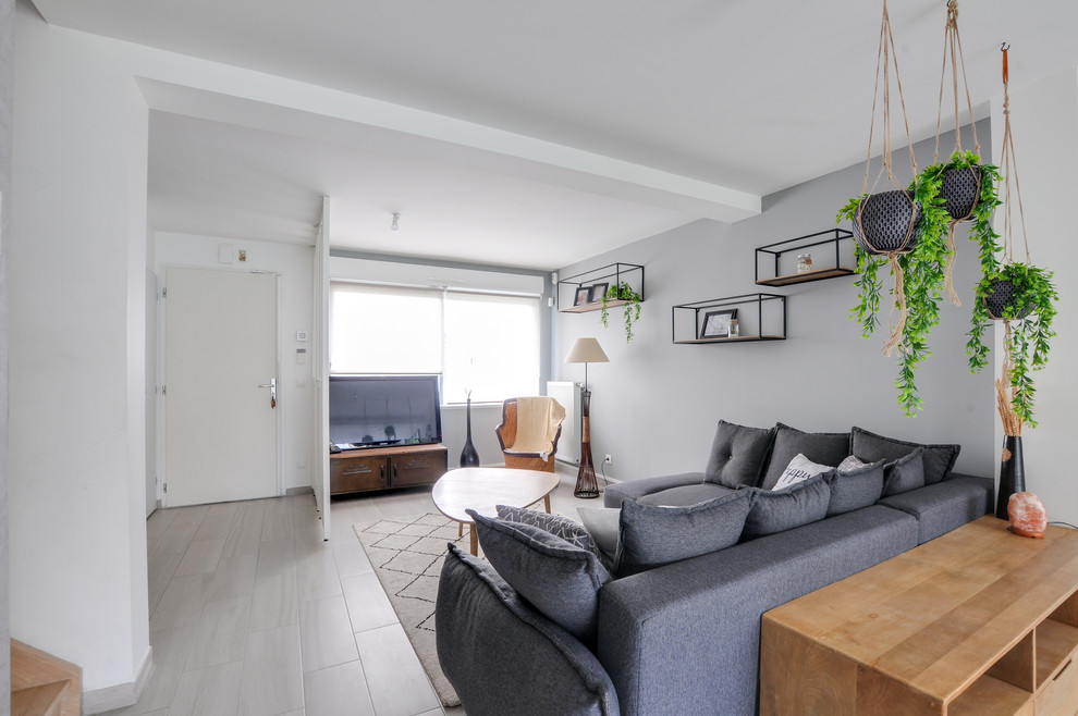 Example of a danish open concept ceramic tile and gray floor living room design in Strasbourg with gray walls, no fireplace and a tv stand