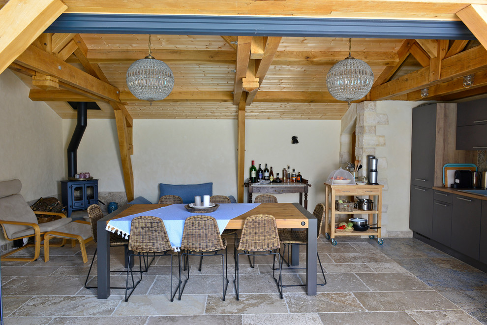 Cette photo montre un salon nature de taille moyenne et ouvert avec un mur beige, un sol en calcaire, un poêle à bois, un manteau de cheminée en métal et un sol beige.