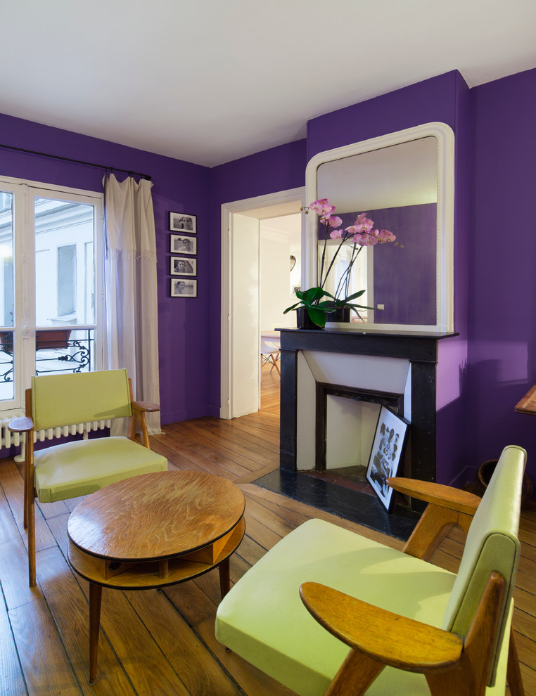 Пример оригинального дизайна: гостиная комната в стиле фьюжн с фиолетовыми стенами, паркетным полом среднего тона и угловым камином