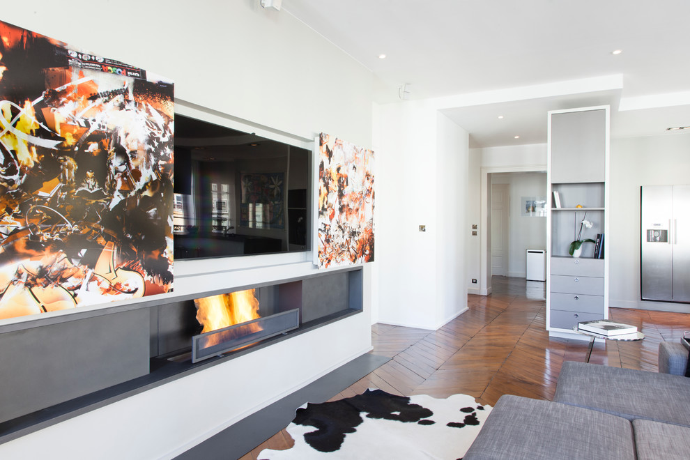 Идея дизайна: двухуровневая гостиная комната среднего размера в современном стиле с бежевыми стенами, темным паркетным полом, фасадом камина из металла и скрытым телевизором