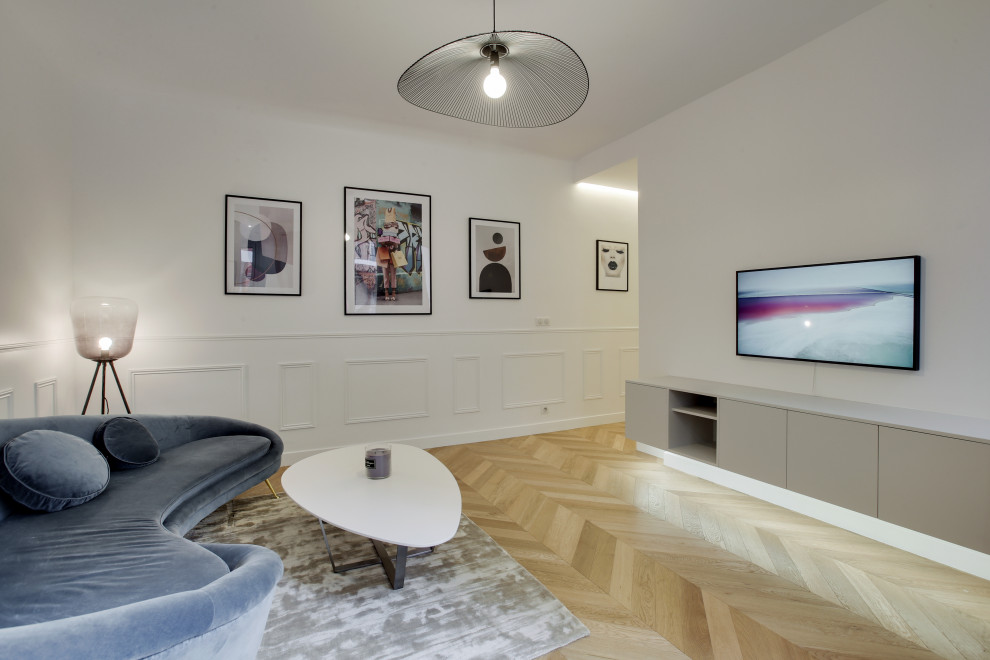 Modern inredning av ett mellanstort allrum med öppen planlösning, med vita väggar, ljust trägolv och en väggmonterad TV