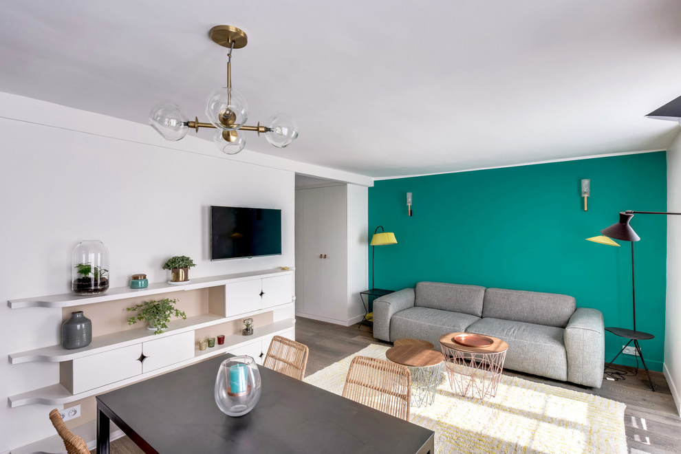 Cette image montre un salon design de taille moyenne et ouvert avec un mur bleu, parquet foncé et un téléviseur fixé au mur.