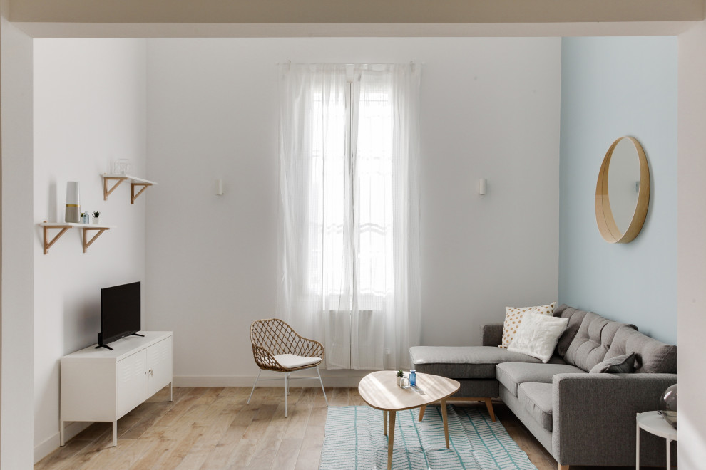 Aménagement d'un grand salon mansardé ou avec mezzanine scandinave avec un mur bleu, parquet clair, un sol marron et un plafond décaissé.