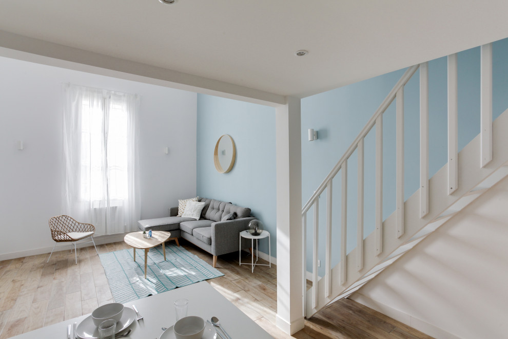 Exemple d'un grand salon mansardé ou avec mezzanine scandinave avec un mur bleu, parquet clair, un sol marron et un plafond décaissé.
