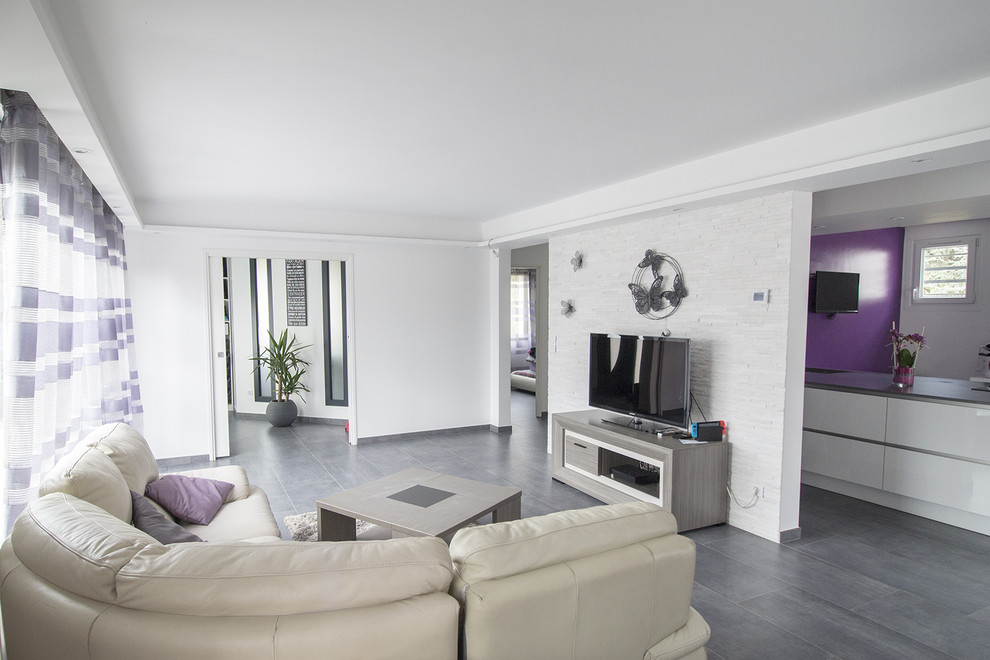 Modern inredning av ett stort separat vardagsrum, med vita väggar, klinkergolv i keramik, en fristående TV och grått golv