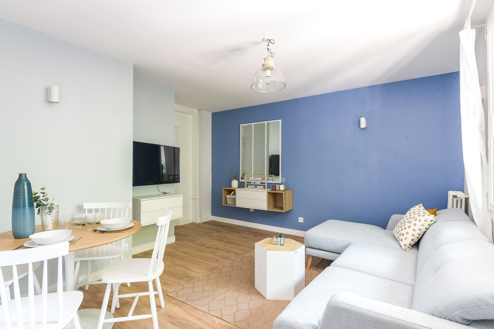 Inspiration pour un salon nordique de taille moyenne et ouvert avec un mur bleu, parquet clair et un téléviseur fixé au mur.