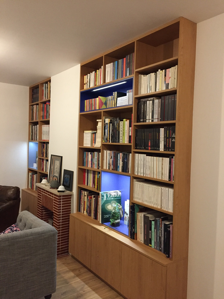 Foto di un grande soggiorno minimalista aperto con libreria, pareti bianche, parquet chiaro, camino classico, cornice del camino in mattoni e nessuna TV