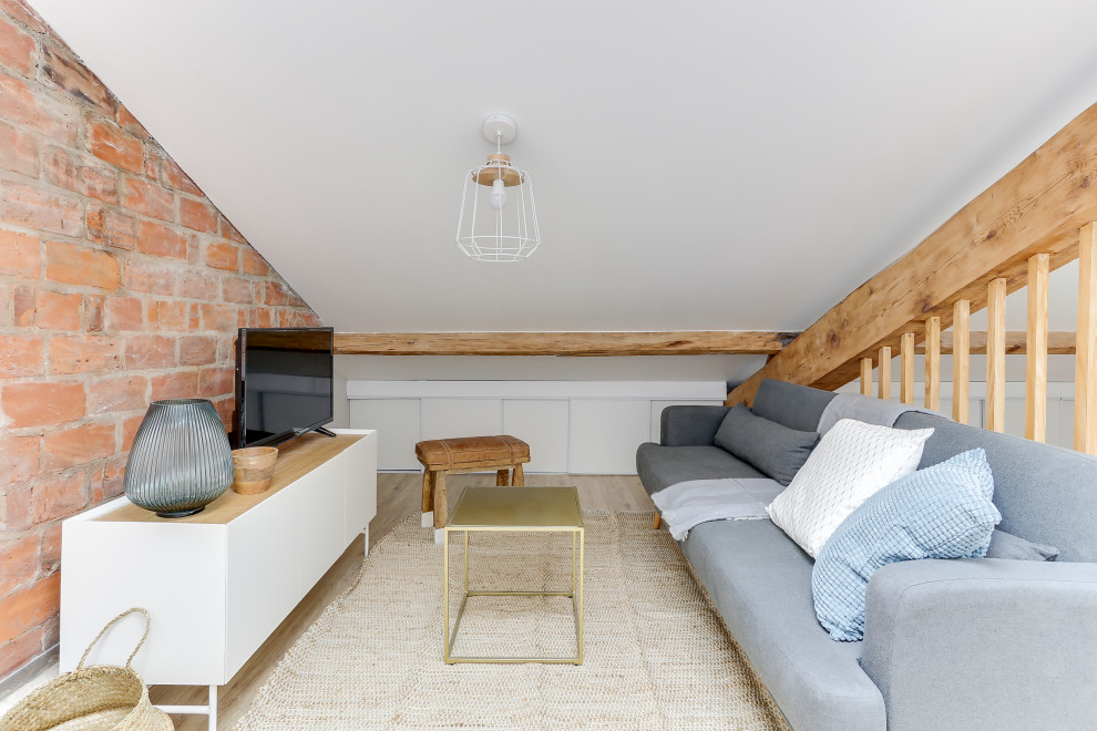 Example of a small danish loft-style light wood floor, exposed beam and wood wall living room design in Marseille with multicolored walls and a brick fireplace