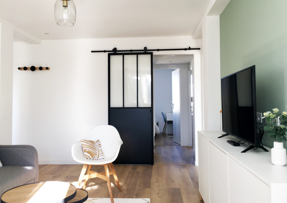This is an example of a small scandi open plan living room in Marseille with green walls, laminate floors and brown floors.