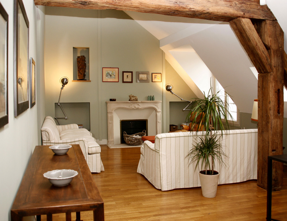 Diseño de salón abierto tradicional de tamaño medio sin televisor con paredes verdes, suelo de madera en tonos medios, todas las chimeneas y marco de chimenea de piedra