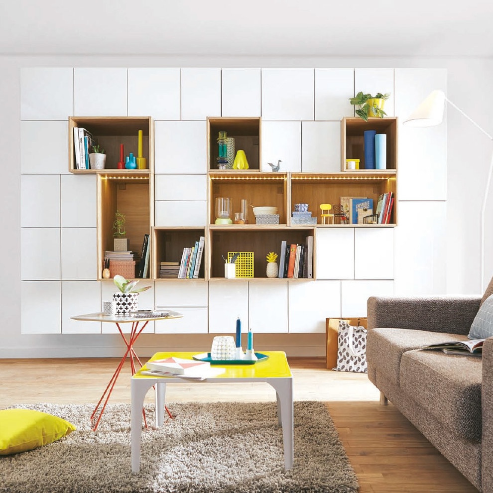 Cette image montre un salon minimaliste de taille moyenne et ouvert avec une bibliothèque ou un coin lecture, un mur blanc, un sol en bois brun, aucune cheminée et aucun téléviseur.