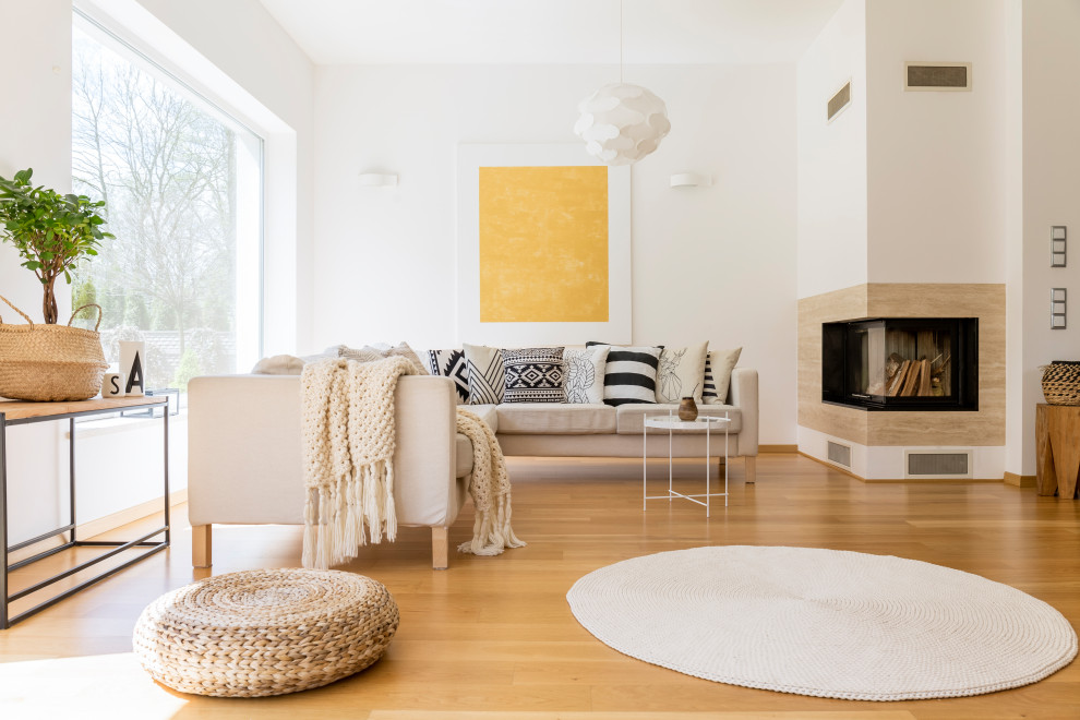 Inspiration pour un grand salon design ouvert avec un mur blanc, parquet clair, une cheminée d'angle, un manteau de cheminée en bois et un sol beige.