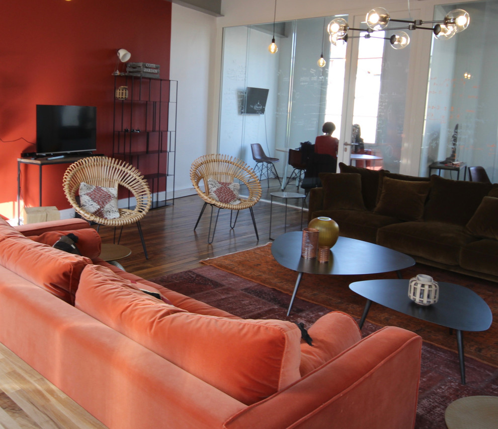 Foto di un ampio soggiorno industriale con pareti arancioni, parquet chiaro e TV autoportante