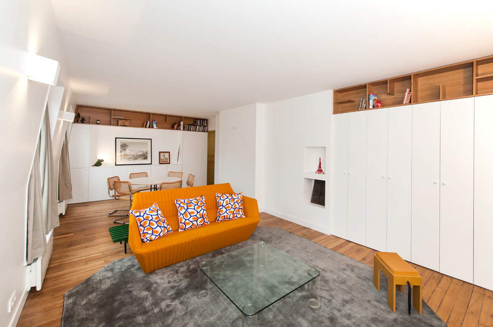 Trendy open concept medium tone wood floor and brown floor living room photo in Paris with white walls